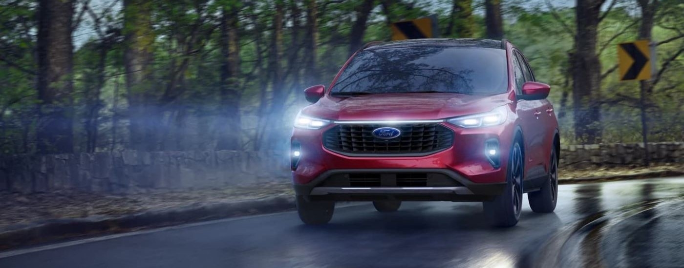 A red 2024 Ford Escape is shown rounding a wet corner at night.