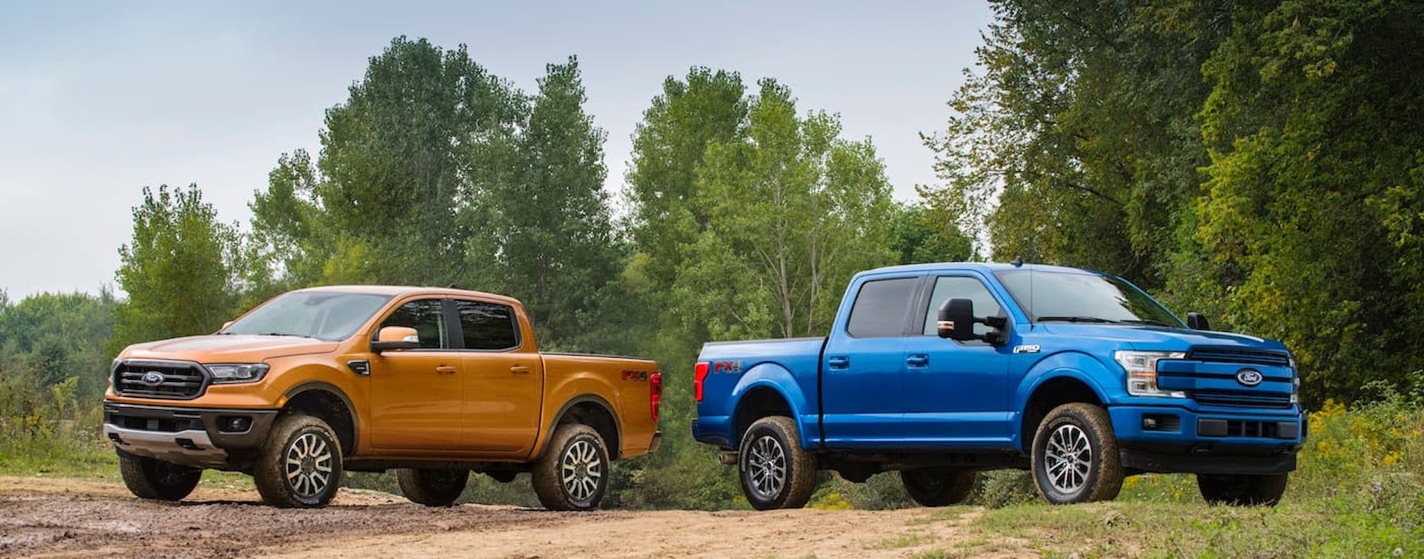 A yellow 2019 Ford Ranger and a blue 2019 Ford F-150 are shown parked off-road.