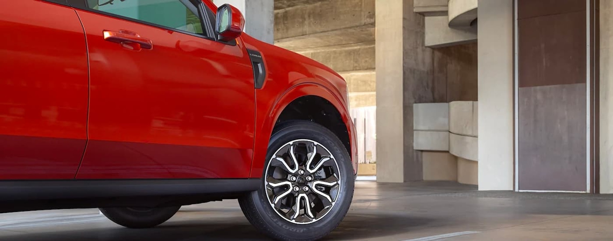 A close up shows the front passenger side of a red 2022 Ford Maverick parked at a Ford dealer.