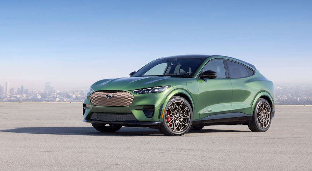 A green 2024 Ford Mustang Mach-E GT is shown from the front at an angle after leaving a Ford dealer near Claremont.