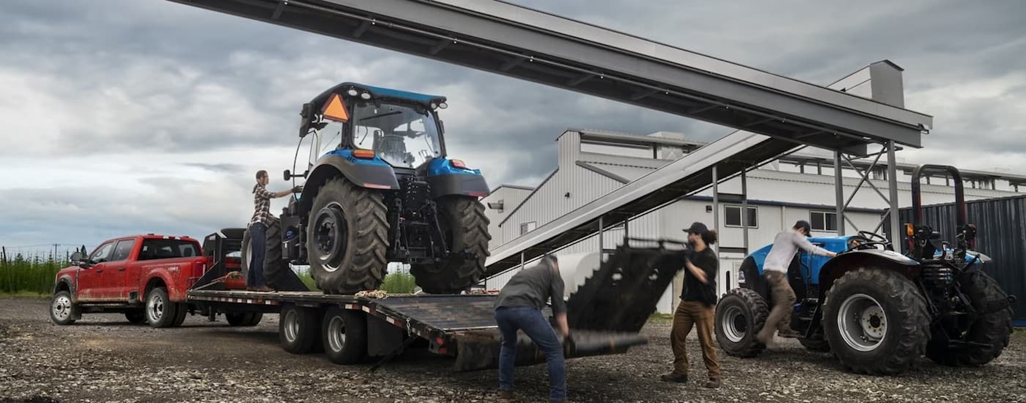 A red 2024 Ford Super Duty F-450 is shown towing a trailer with a blue tractor on it.