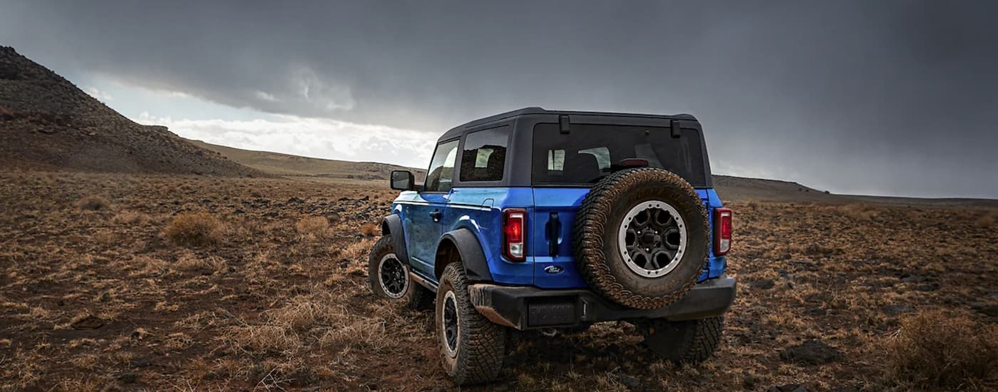 A blue 2023 Ford Bronco Black Diamond is shown from the rear overlooking a dry grassy field.