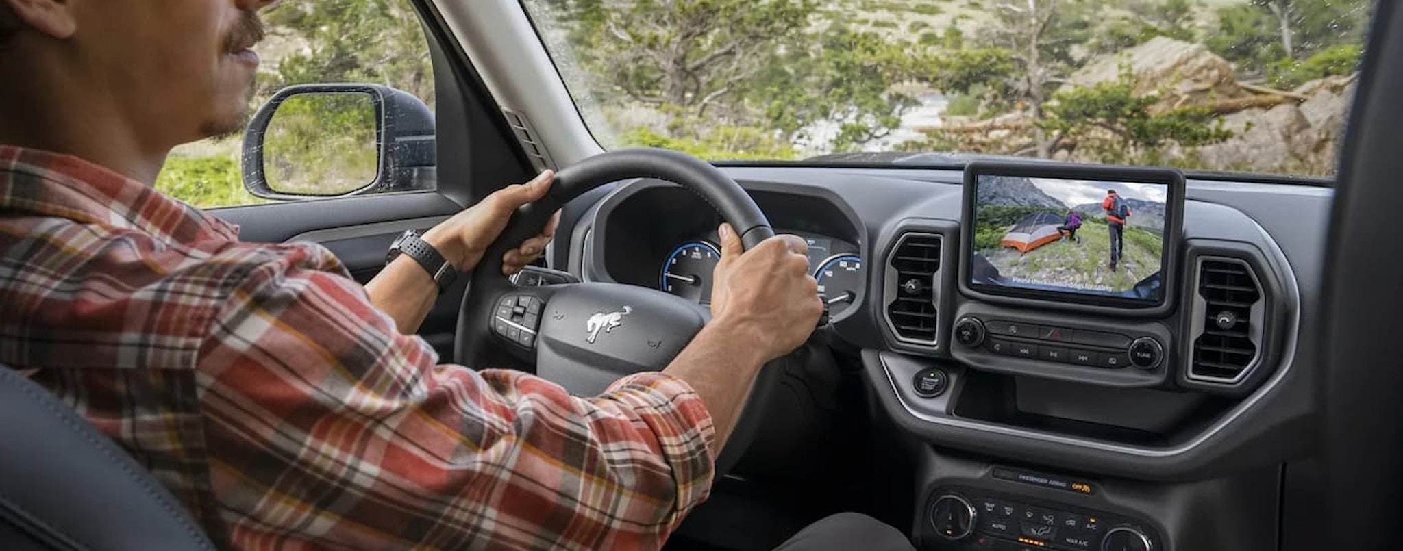 A man is shown in the front seat of a 2023 Ford Bronco Sport while viewing the backup camera.