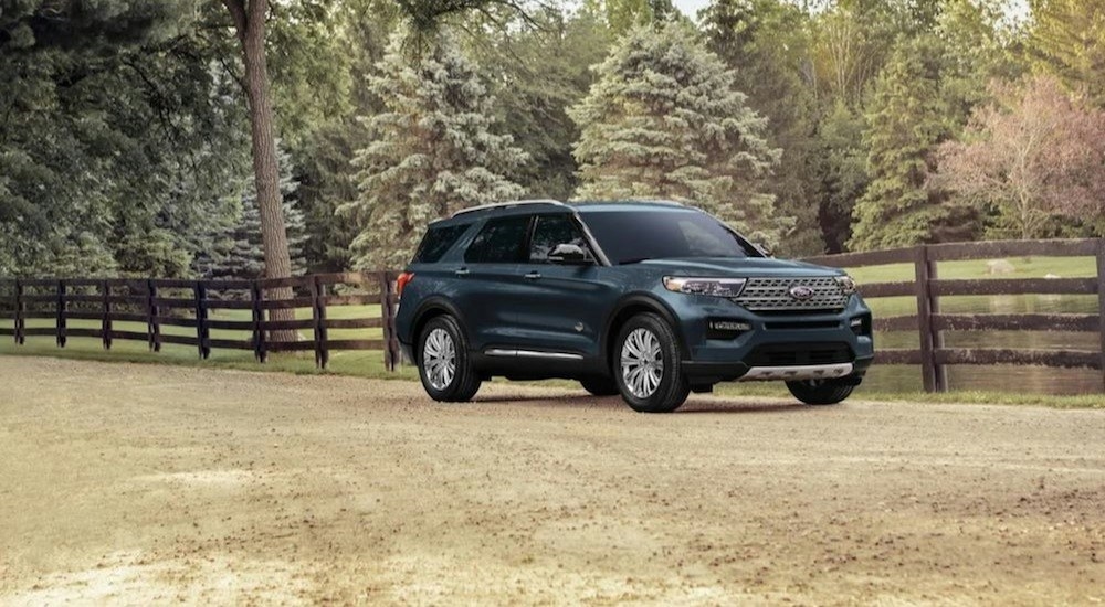 A blue 2023 Ford Explorer King Ranch is shown parked near a fence.