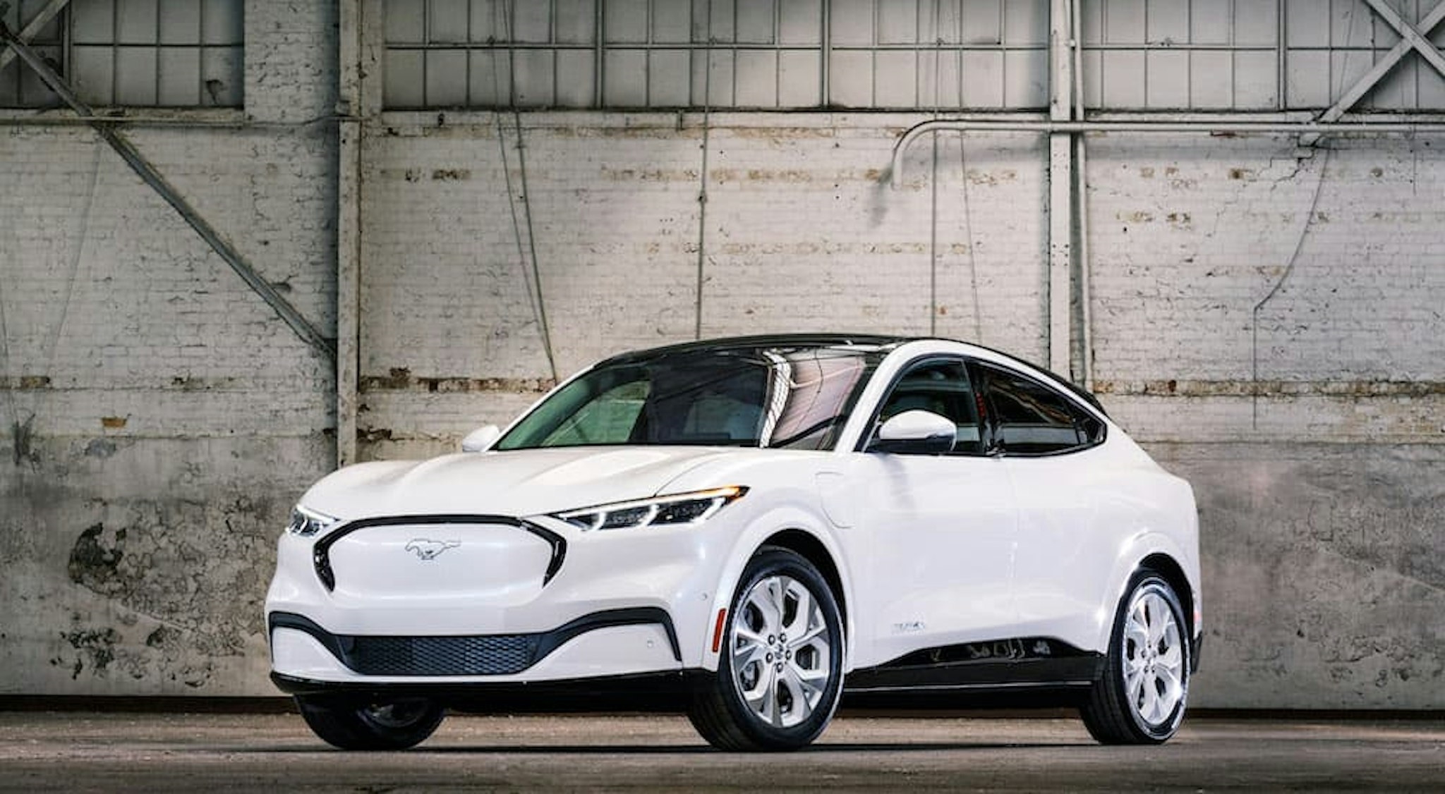 A white 2022 Ford Mustang Mach-E is shown from the front at an angle after leaving a dealer that has electric vehicles for sale.