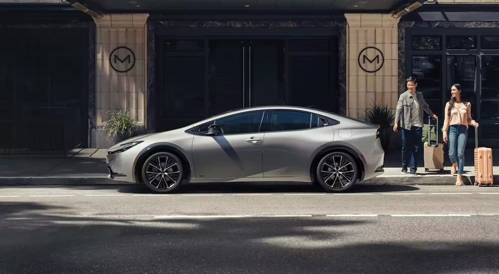 A silver 2023 Toyota Prius is shown from the side on a city street after the driver decided to rent a Toyota.