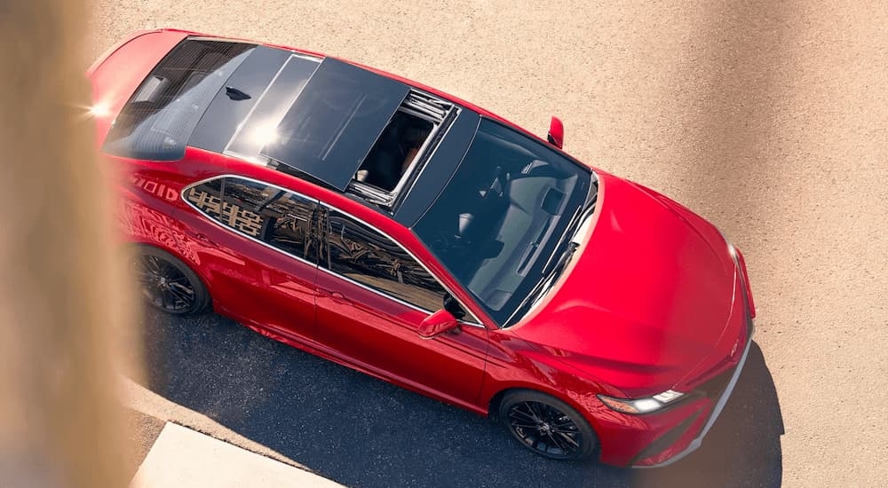 A red 2022 Toyota Camry XSE parked below an apartment window.