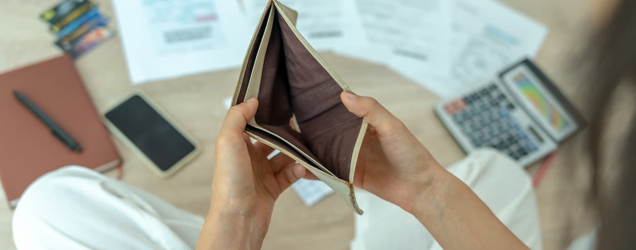 A person is shown looking into an empty wallet.