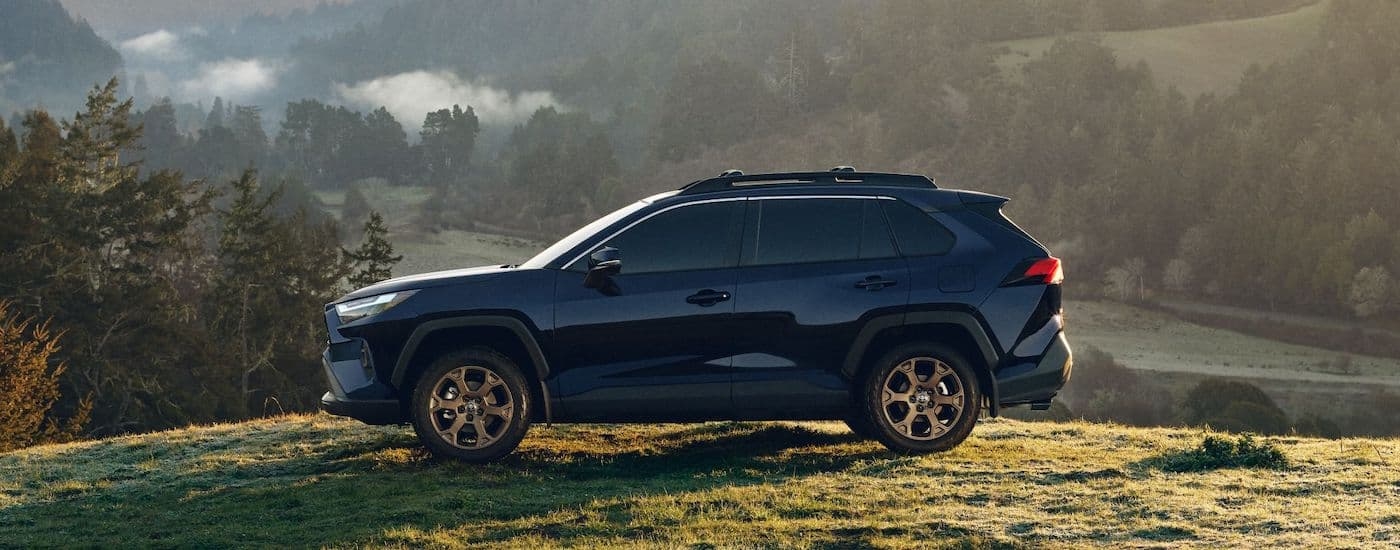 A blue 2023 Toyota RAV4 is shown from the side while off-road.
