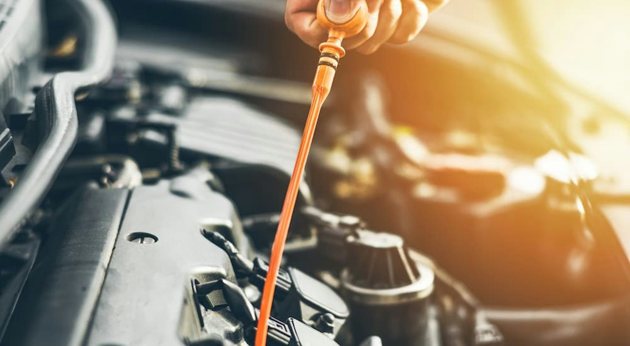 A mechanic is shown checking the oil on a car.