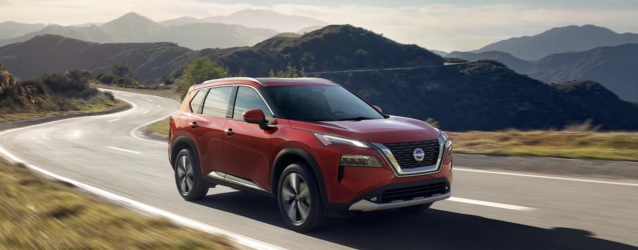 A red 2022 Nissan Rogue is shown from the front at an angle after leaving a dealer that has a used Nissan for sale.