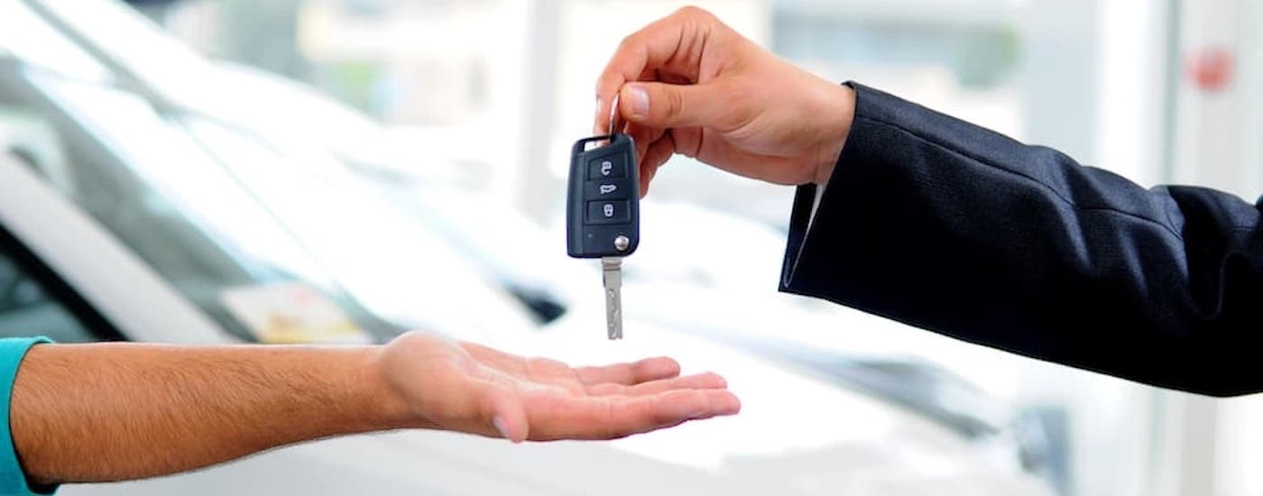 A salesmen is shown handing over keys to a customer.