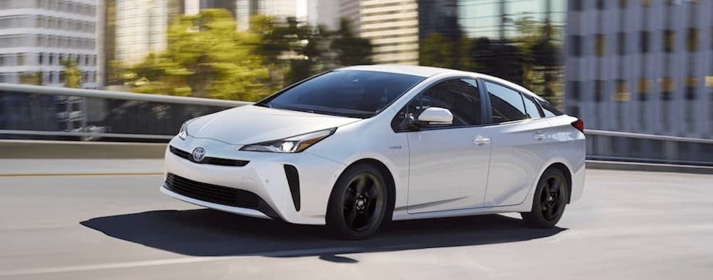 A white 2020 Toyota Prius is shown driving on a bridge.