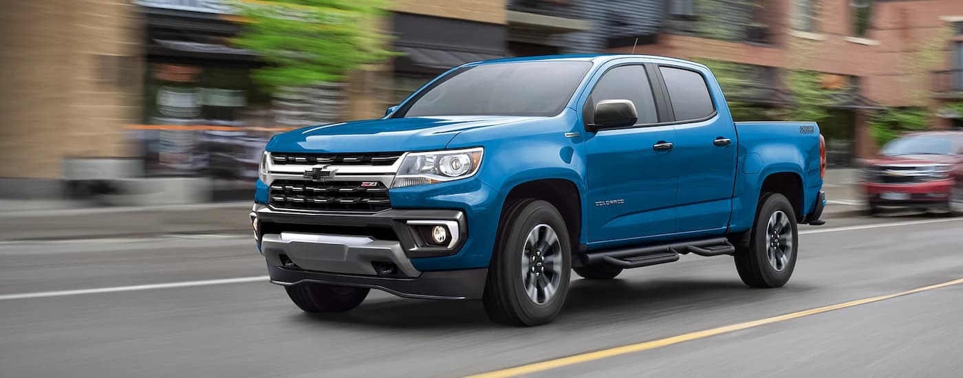 A blue 2022 Chevy Colorado Z71 is shown driving on a city street.