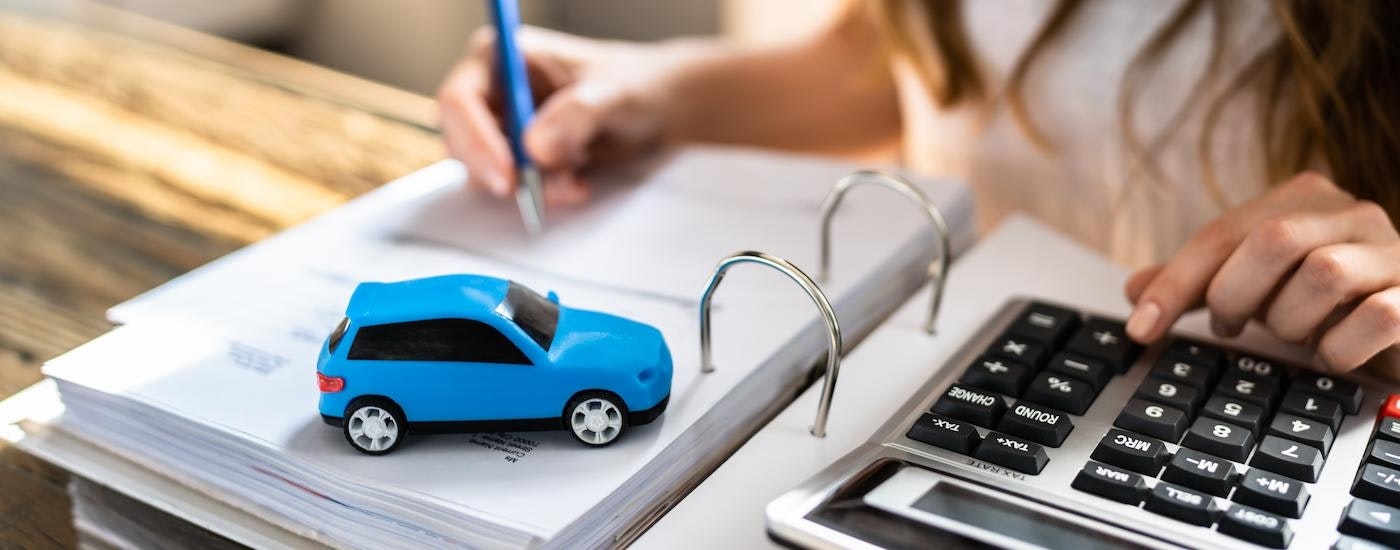 A person is shown using a calculator while doing financing paperwork.