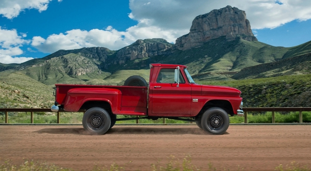 A red 1960 Chevy C/K is shown from the side on a dirt road.