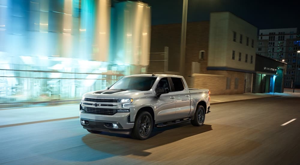 A silver 2020 Chevy Silverado 1500 Rally Edition is shown driving on a city street.