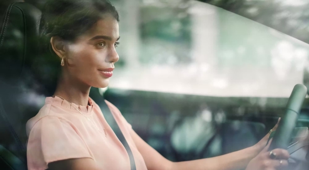 A smiling person is shown driving a 2023 Toyota bZ4X Limited.