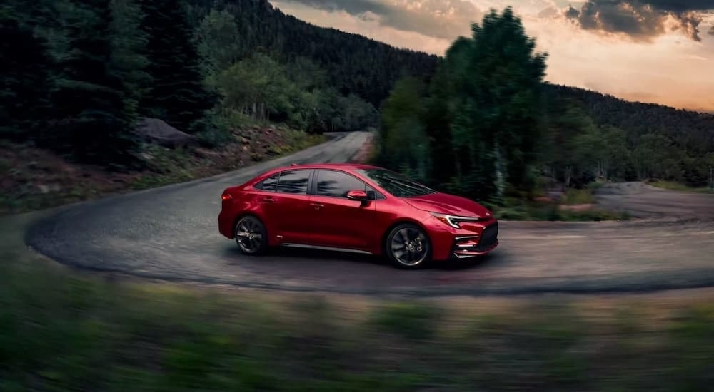 A red 2023 Toyota Corolla rounding a bend.