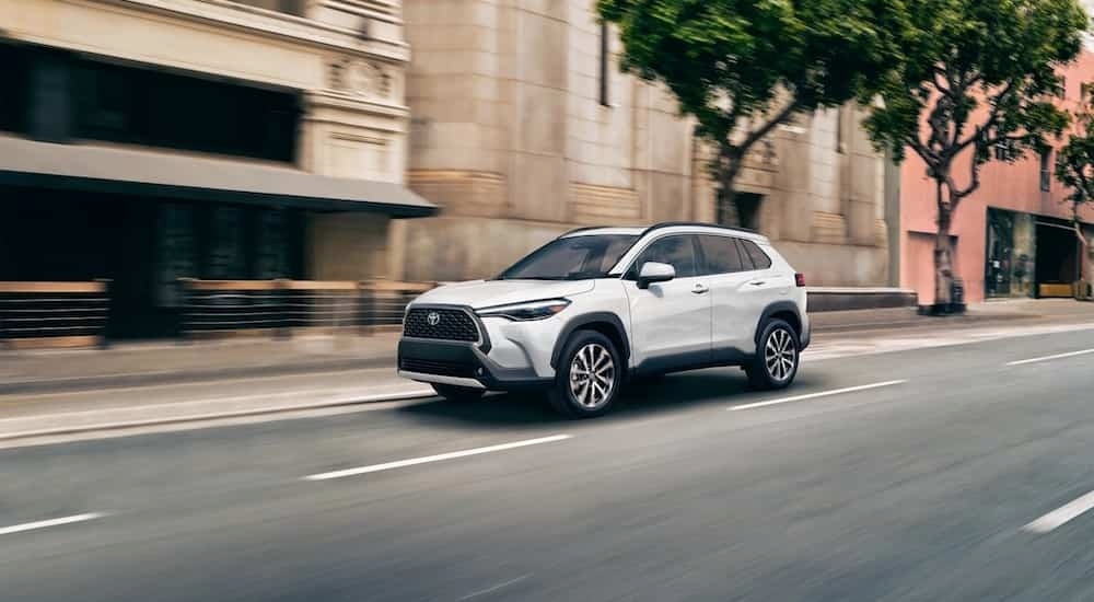 A white 2022 Toyota Corolla Cross driving in a city.