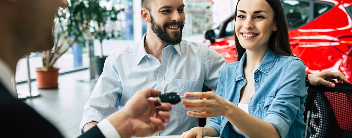 A smiling couple is shown shopping for bad credit car loans near Bennington