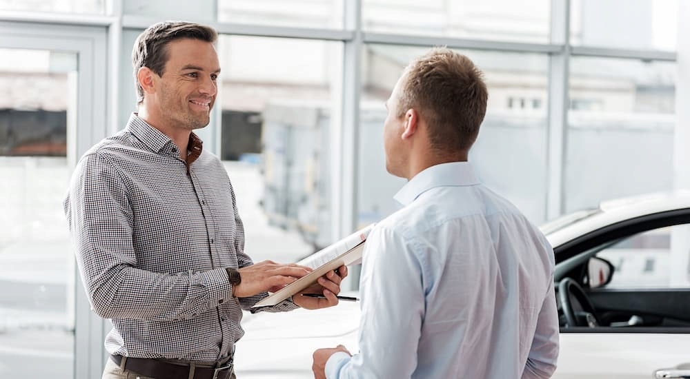 People are shown having a discussion at a car dealer.