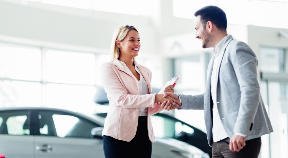 Smiling people are shown at a dealership providing bad credit car loans near Bennington.