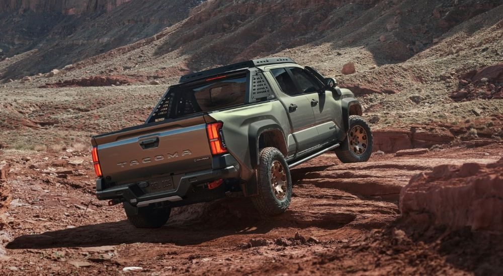 A green 2024 Toyota Tacoma TrailHunter is shown from the rear at an angle after leaving a dealer that has a Toyota Tacoma for sale.