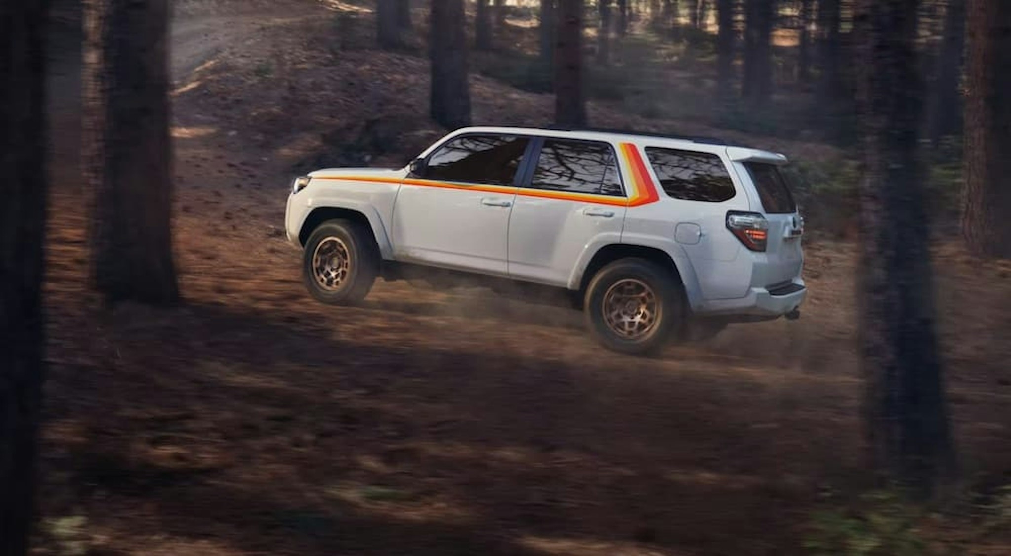 A white 2023 Toyota 4Runner Anniversary Edition driving off-road.