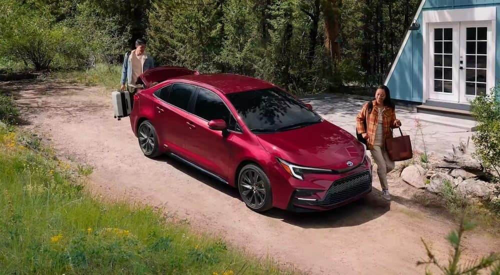 A red 2023 Toyota Corolla parked near an A-frame house.