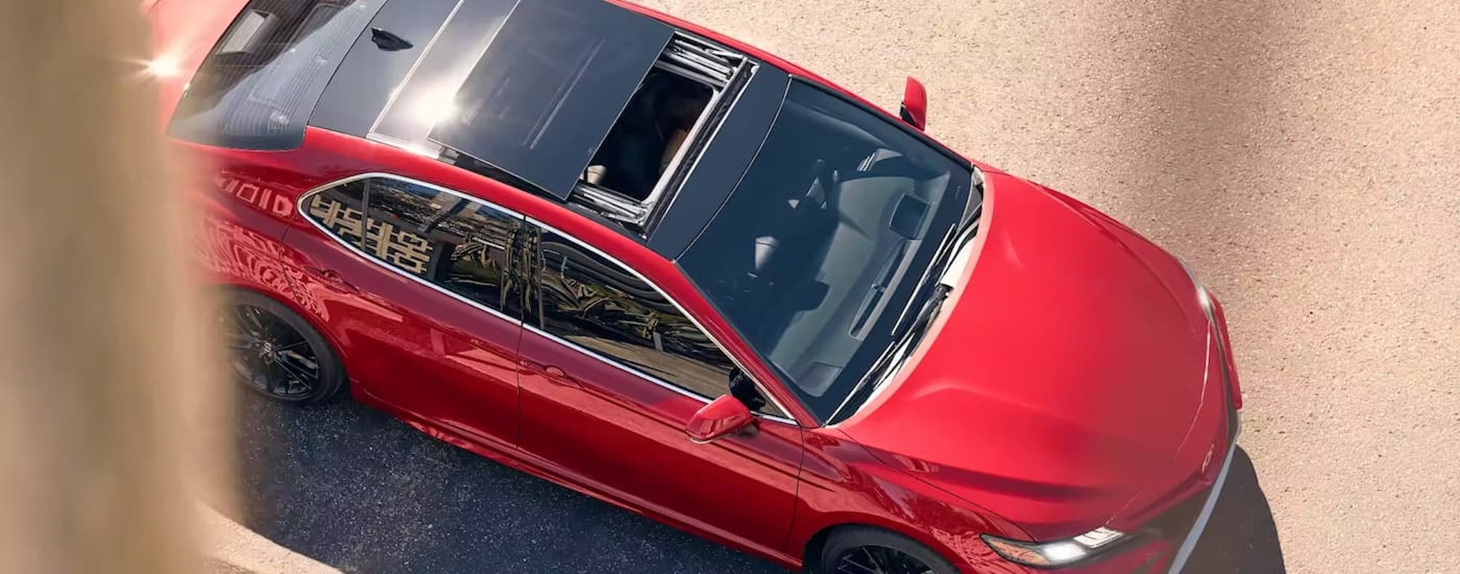 A red 2023 Toyota Camry XSE V6 is shown from above parked on the side of a city street.