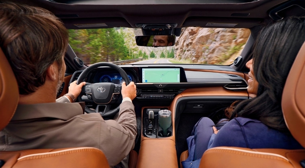 A man and a woman are shown sitting in the front seats of a 2025 Toyota Crown Signia.