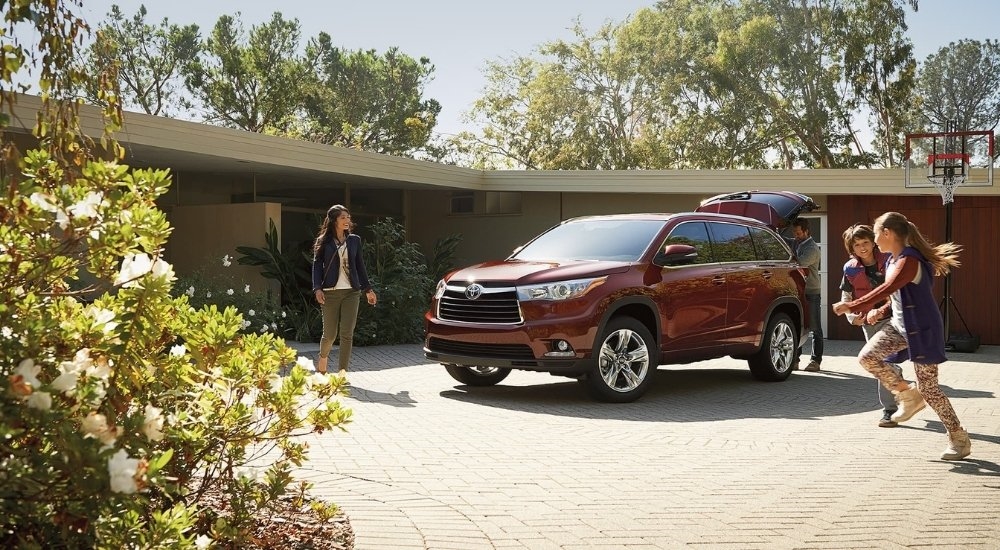 A red 2016 Toyota Highlander is shown on a driveway.