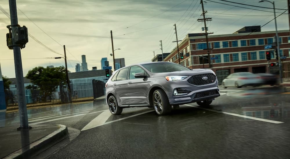 A grey 2022 Ford Edge ST driving in a city.