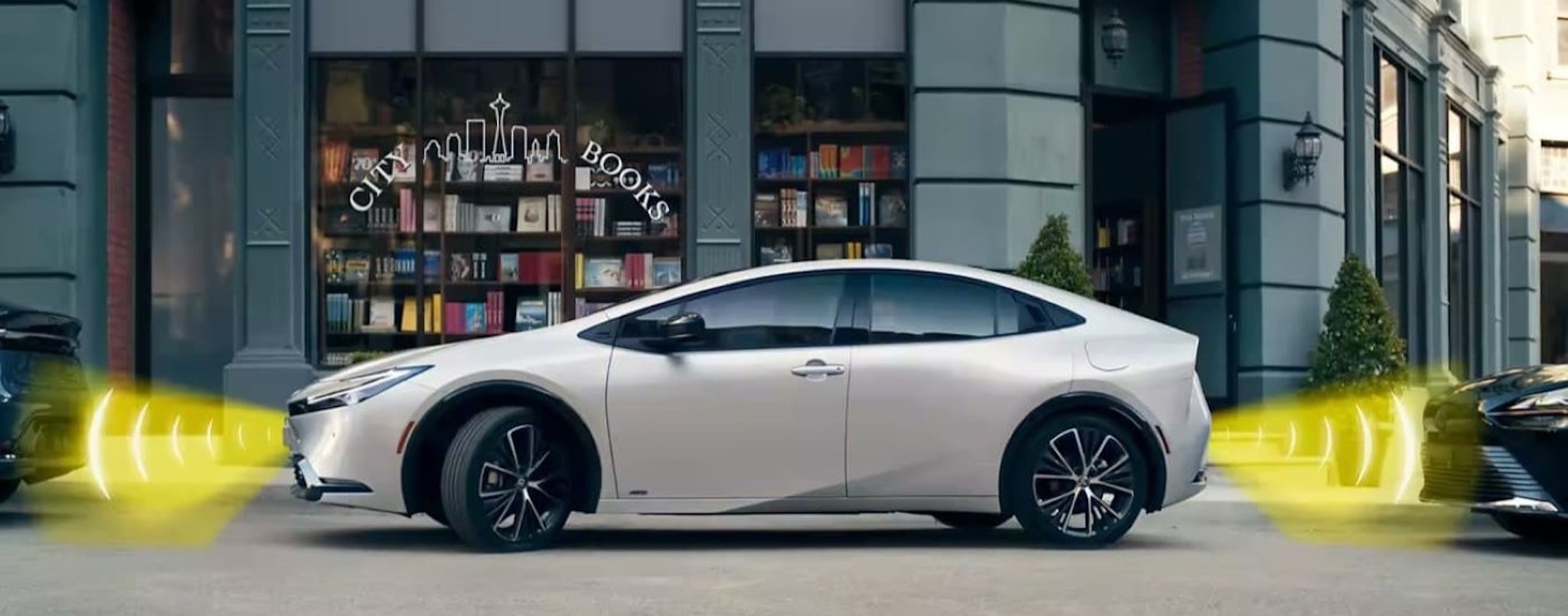 A silver 2023 Toyota Prius Limited is shown parallel parking with simulated sensor lines.