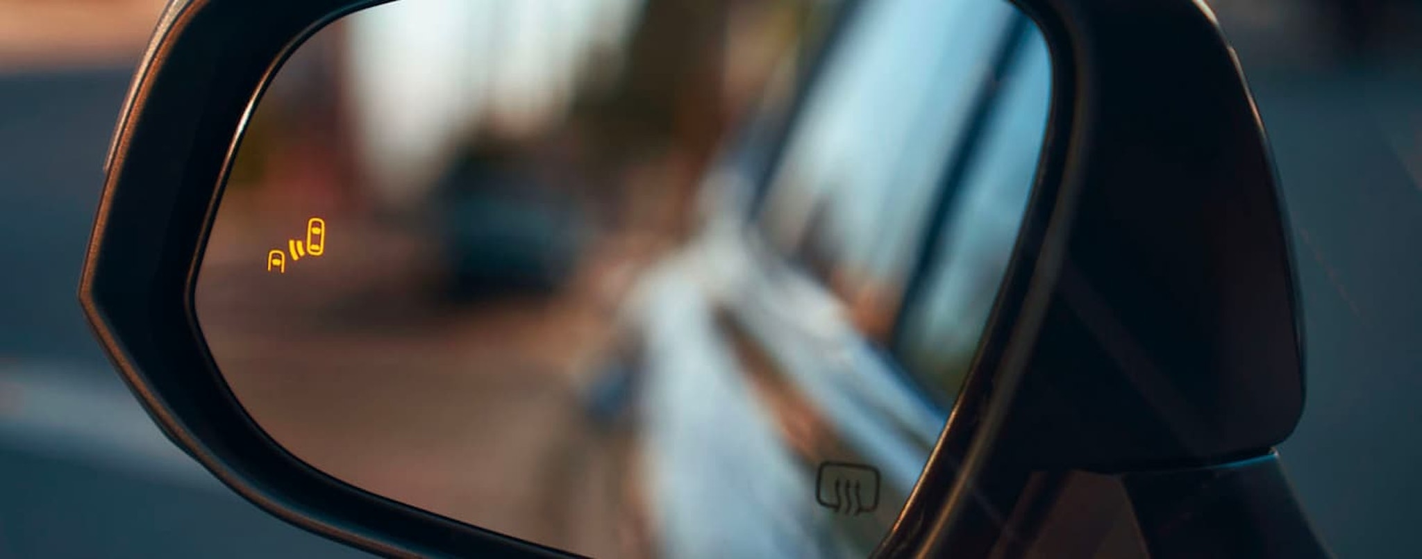 A close up shows the illuminated blind spot monitoring icon on a 2023 Toyota Highlander Platinum.