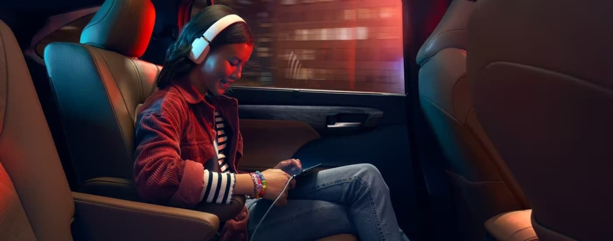 A young girl with headphones is shown listening to music in a 2023 Toyota Highlander.