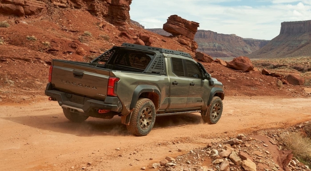 A green 2024 Toyota Tacoma Trailhunter is shown from the rear after leaving a Toyota dealer near Walpole.