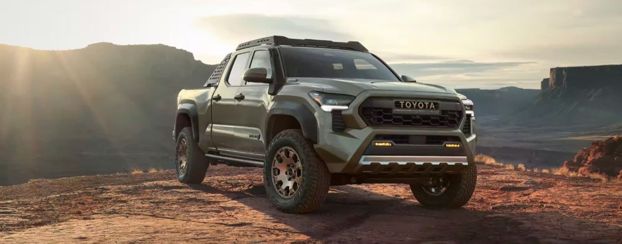 A green 2024 Toyota Tacoma Trailhunter is shown on a sunny day.