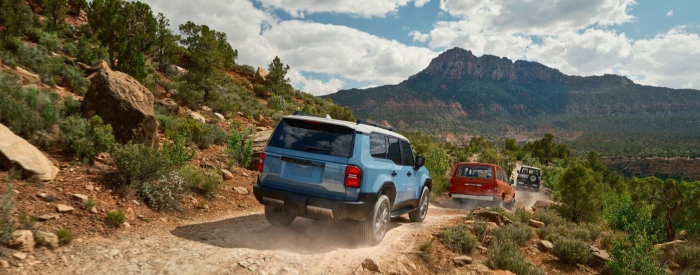 A blue 2024 Toyota Land Cruiser is shown from the rear off-roading.