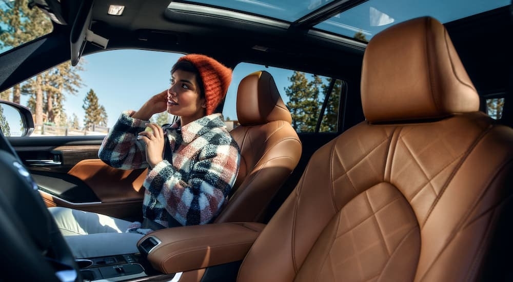 A woman sitting in the passenger seat of a used 2020 Toyota Highlander Hybrid for sale.