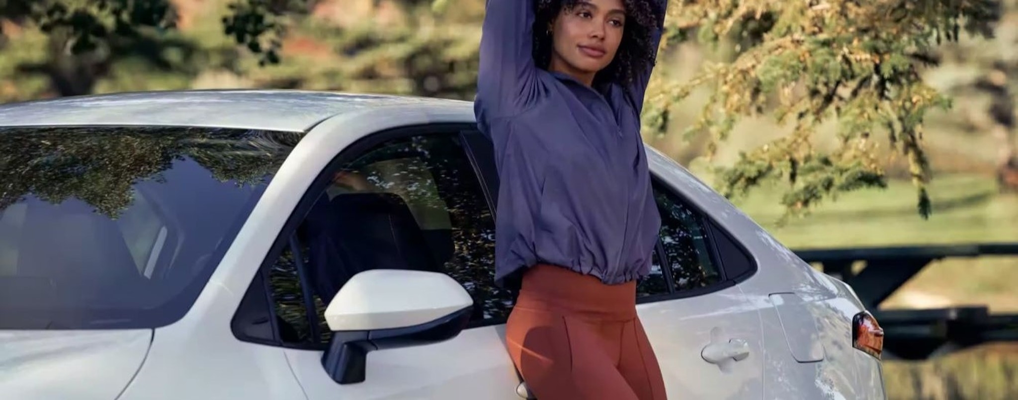 A person is shown leaning against a white 2023 Toyota Corolla LE.