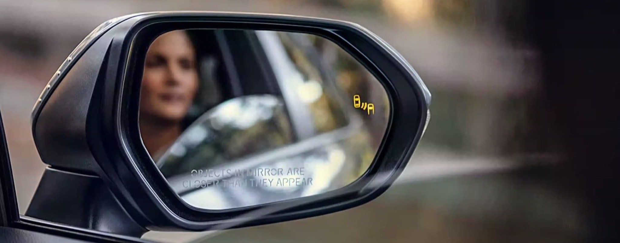 The blind spot monitoring icon is shown on the mirror of a grey 2023 Toyota Corolla XSE.