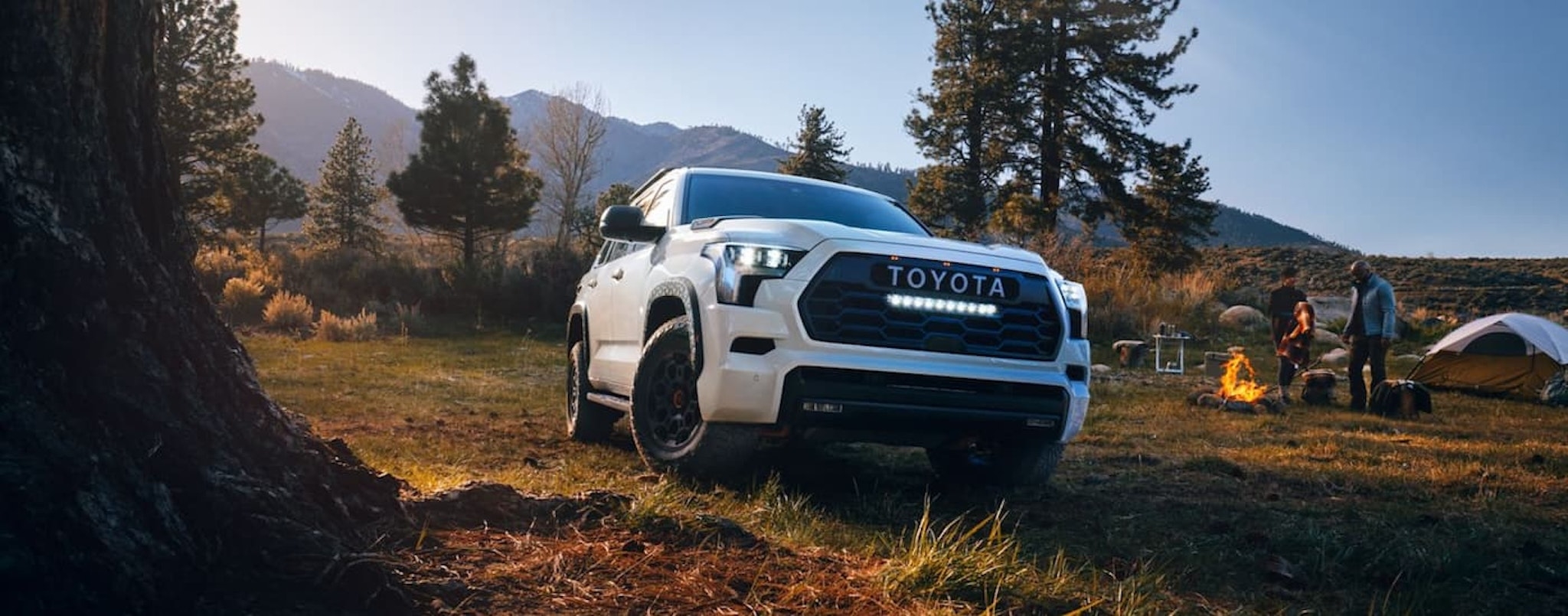 A white 2024 Toyota Sequoia TRD Pro is shown parked near a campsite.