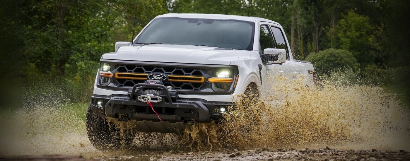 A white 2025 Ford F-150 Tremor is shown splashing through a puddle.