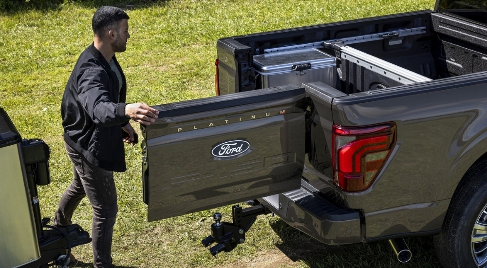 A person is shown opening the tailgate of a grey 2025 Ford F-150 Platinum.