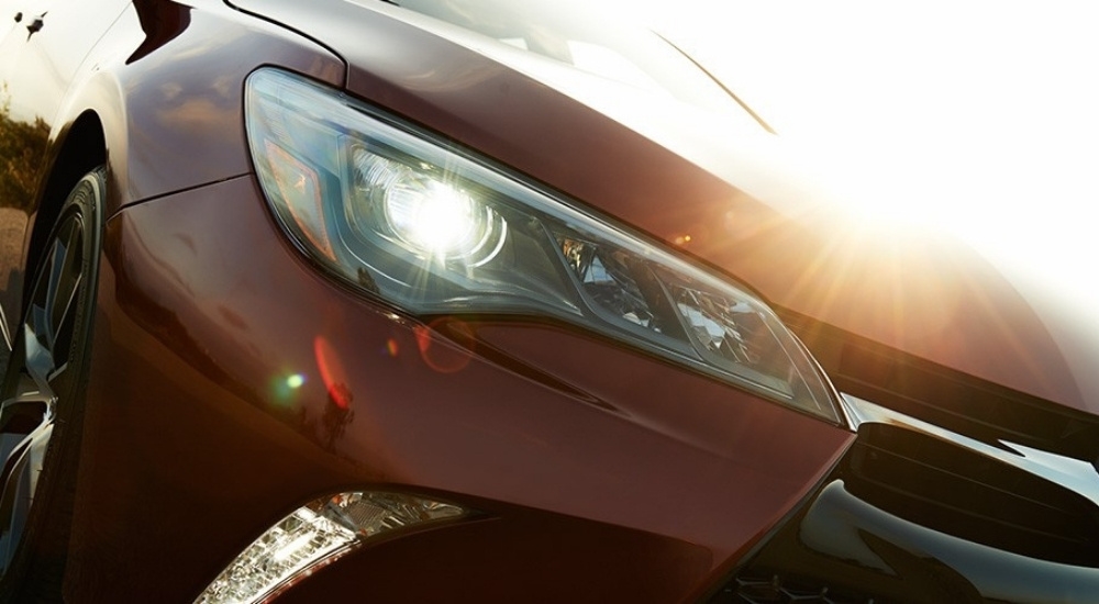 A close-up shows the headlight on a red 2016 Toyota Camry.