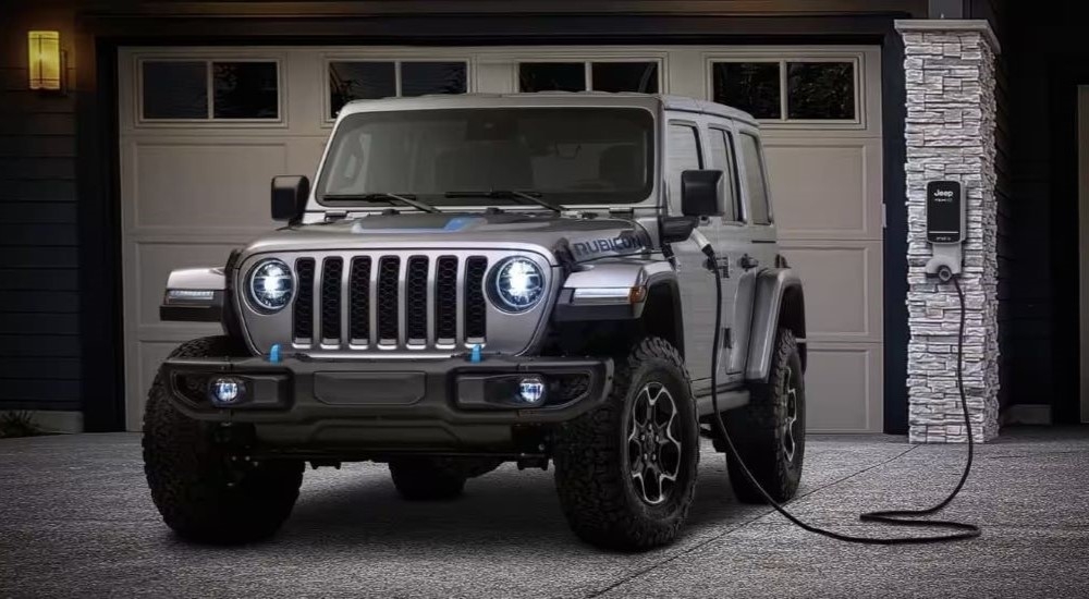 A grey Jeep Wrangler 4xe Rubicon parked on a driveway and charging.