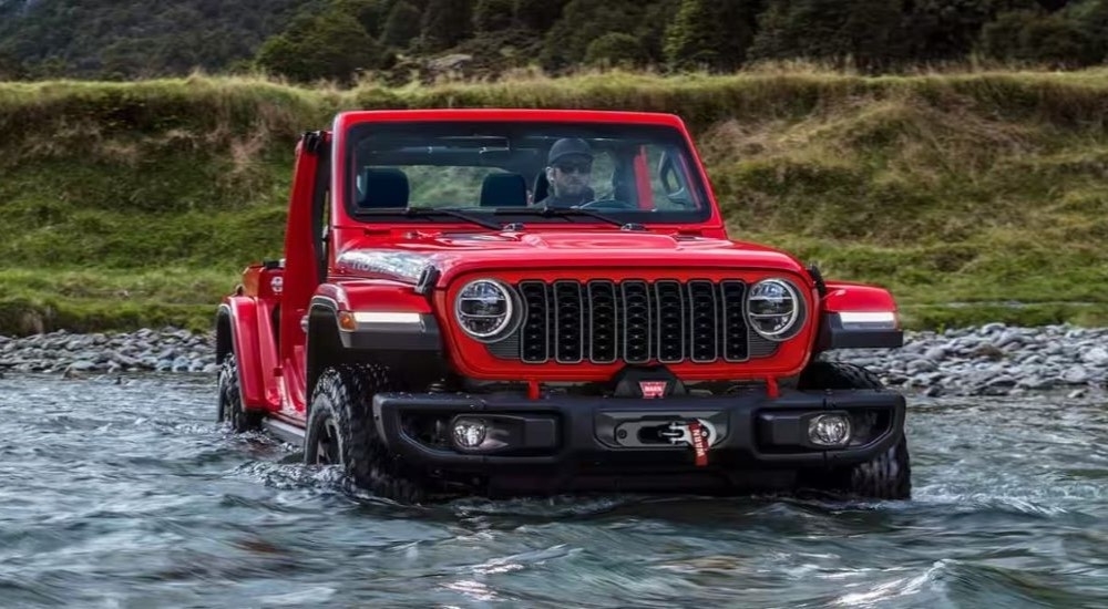 A red 2024 Jeep Wrangler Rubicon fording a river.