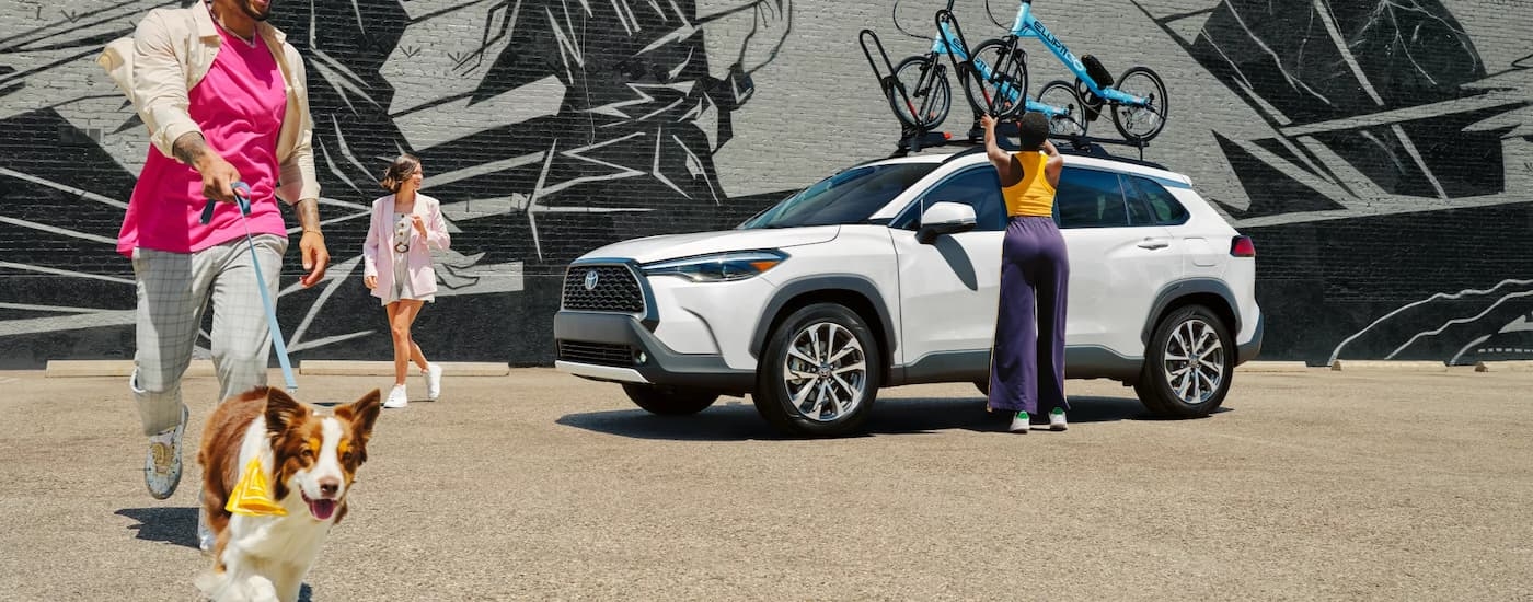 A white 2024 Toyota Corolla Cross is parked near a wall with a mural.